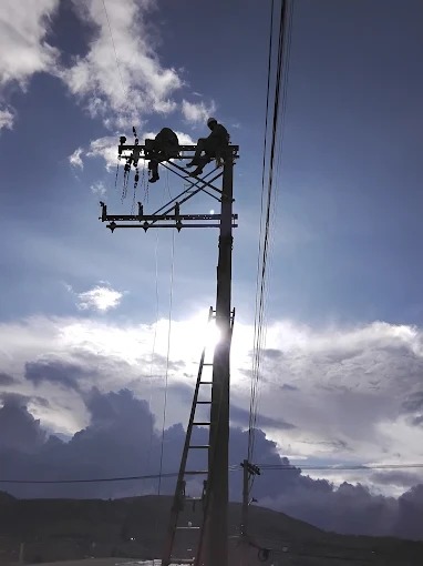 Técnicos trabajando en una red eléctrica al atardecer